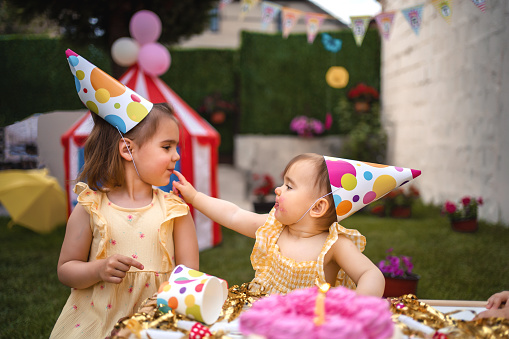 Portrait of smiling young Indian girls making party and celebrating birthday together. Clicking selfie pictures with smartphone