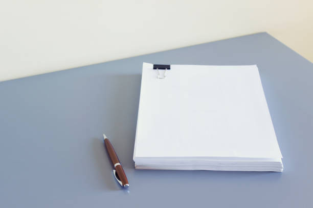 Mockup template with blank A4 paper stack on gray table and metallic parker pen.