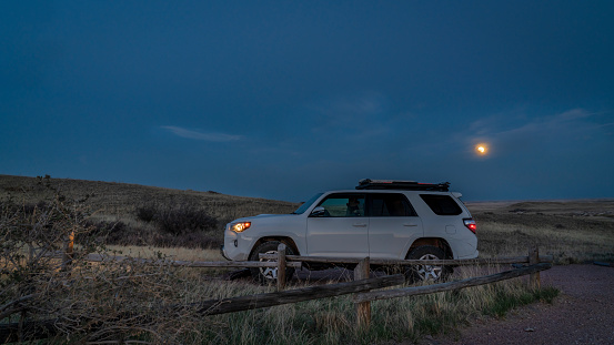 Fort Collins, CO, USA - May 15, 2022: Toyota 4Runner SUV at parked at a trailhead in Soapstone Prairie Natural Area in Colorado foothills, evening with super flower blood moon eclipse.