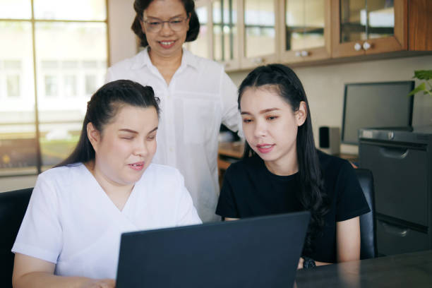 istock Asian women co-workers in workplace including person with blindness disability using laptop computer with screen reader program for visual impairment people. Disability inclusion at work concepts. 1397765921
