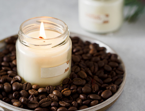 Burning aromatic coffee candle and coffee beans, close-up
