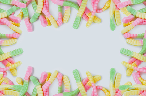 Frame of bright colored chewing candies in the form of worms. White background. Place for text.