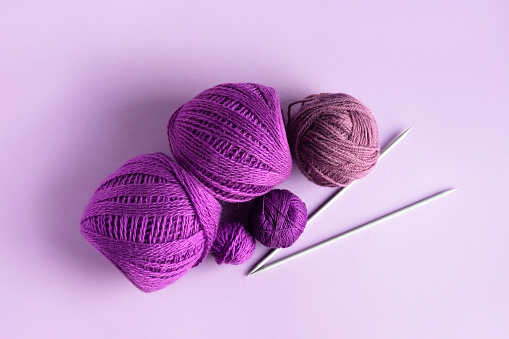 Purple lilac and pink knitted wool on a lilac background for knitting warm clothes and hobbies needlework