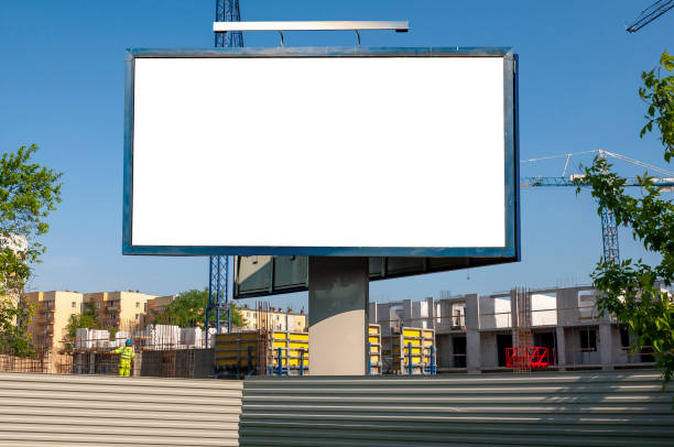 istock Blank white billboard for advertisement in front of the construction site. Apartment building under construction on a sunny day. 1397771428