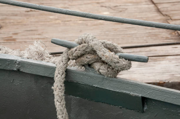 wiązany węzeł linowy na metalowym słupie, porcie morskim. okręt marynarki wojennej jest zacumowany w doku. - moored nautical vessel tied knot sailboat zdjęcia i obrazy z banku zdjęć