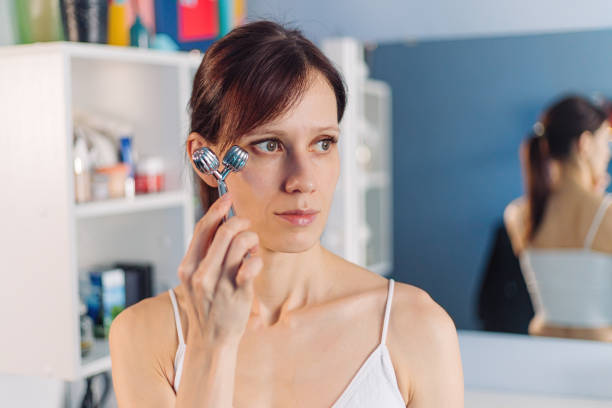 istock Young woman using facial roller for face massage 1397774284