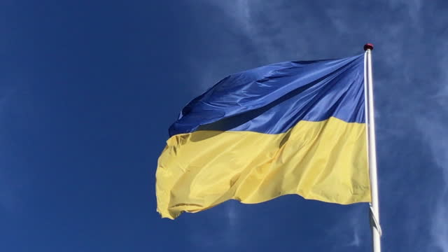 Ukrainian flag waving in the wind against a deep blue sky