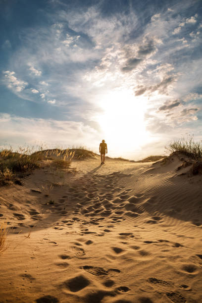 istock Lonely man walking in the desert dunes at sunset. 1397774661