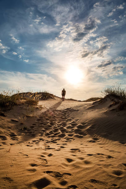 istock Lonely man walking in the desert dunes at sunset. 1397774696