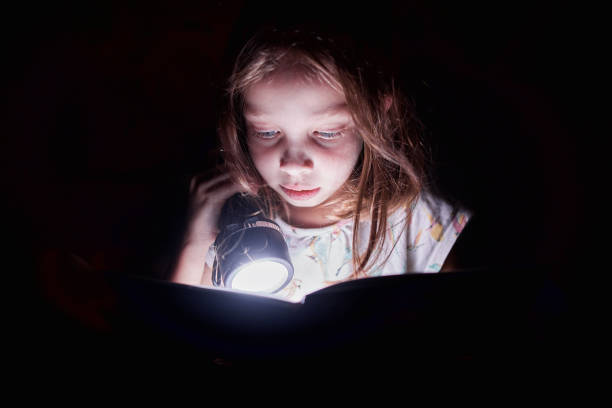 istock little girl reading a book at night with a flashlight 1397777402