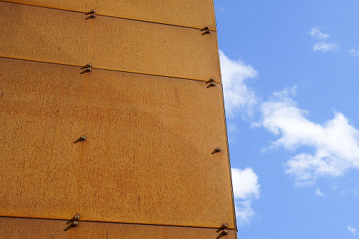 Rusted corten steel panels cladding facade of a modern design house on a background of a blue sky
