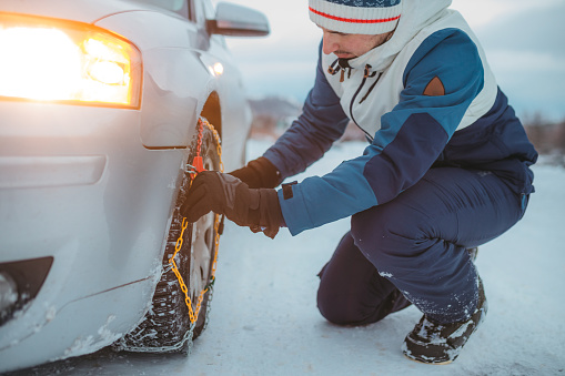 Adult Man Tightening Tire Chains on His Car
