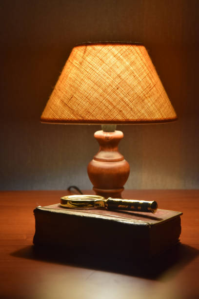 istock Reading lamp, old book and magnifier on the desk. Soft light. Evening time. 1397779153