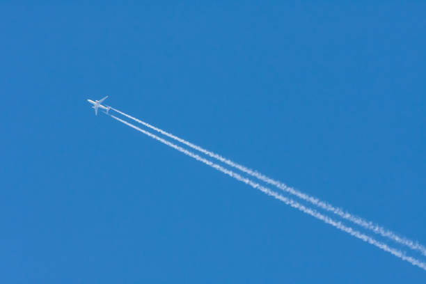 istock Large airliner in the blue sky without clouds. There is a clear line behind the plane. 1397780179