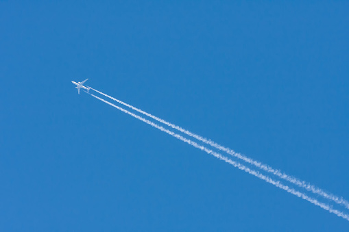 Large airliner in the blue sky without clouds. There is a clear line behind the plane.