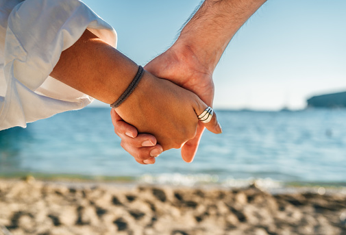 Young caucasian heterosexual couple holding hands on the beach