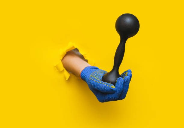 istock A worker's right hand in a blue knitted glove holds a black dumbbell. Torn hole in bright yellow paper. Healthy lifestyle concept avd copy space. 1397781578