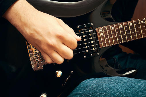 Close-up of man playing electric guitar in music studio
