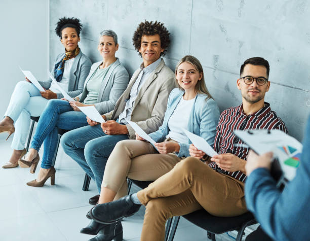 man business chair sitting waiting woman businessman candidate recruitment businesswoman office businessperson job young interview line Group of young business people sitting in chairs and waiting for an interview unemployment stock pictures, royalty-free photos & images