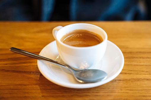 a white cup of coffee on a wooden table. coffee break