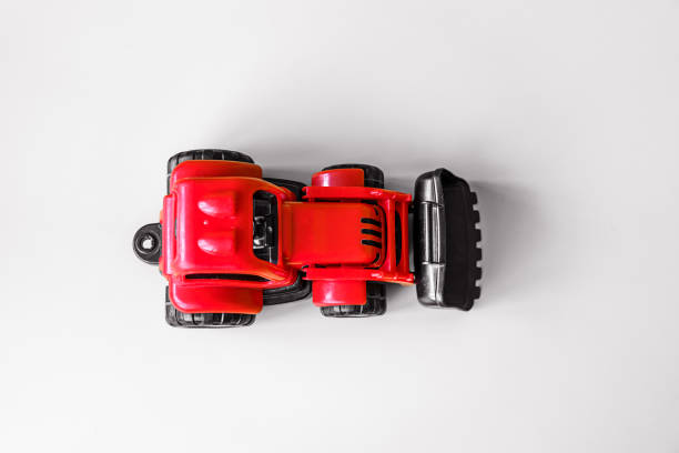 Vintage red colored plastic tractor toy with black scoop isolated on white background top view