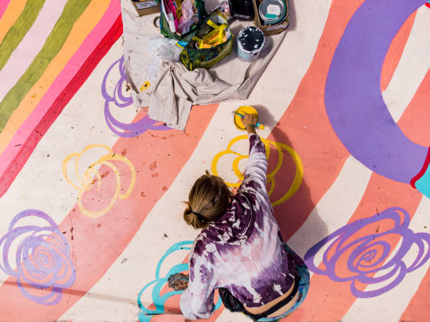 Aerial view of female artist painting sidewalk mural stock photo