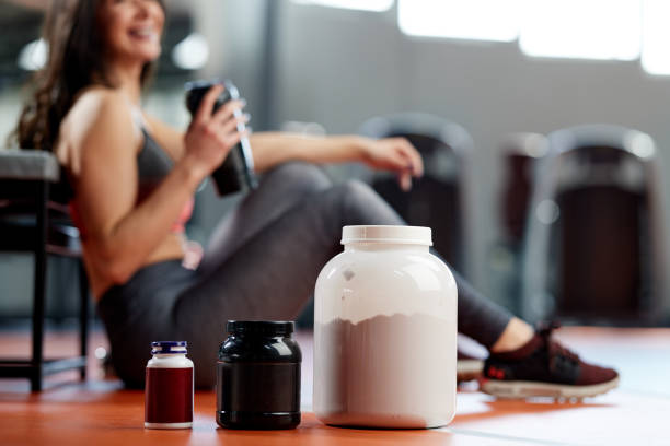 Selective focus on supplements and protein power in gym with a sportswoman. stock photo
