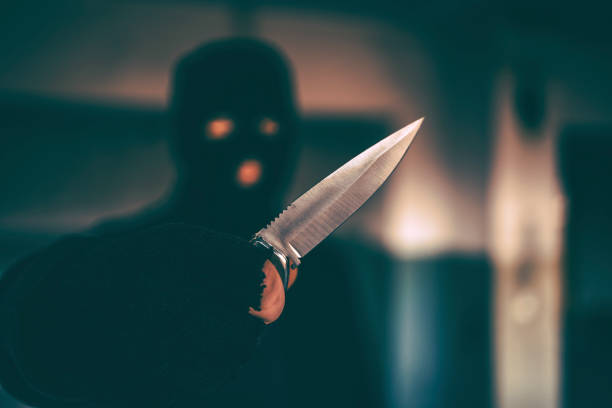 Criminal man in hood with knife outdoors