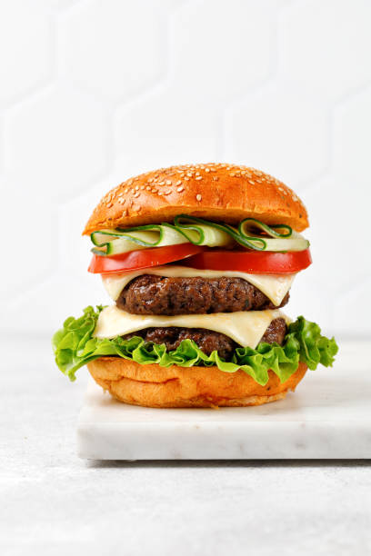 istock Cheese burger with cutlets on marble board with white background. High Cheeseburger 1397785858
