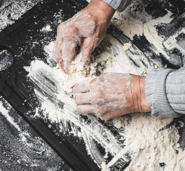 istock two female hands knead the dough from white wheat flour on a black table, top view 1397786630