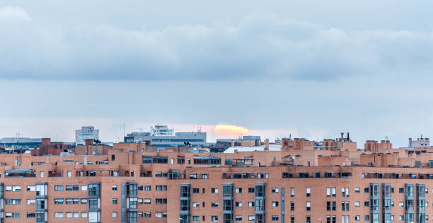 sun hiding behind residential buildings - madrid built structure house spain imagens e fotografias de stock