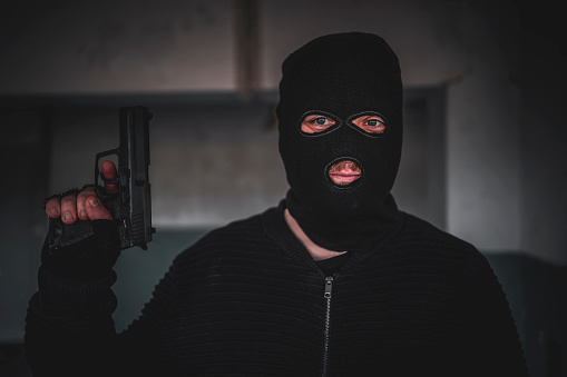 Caucasian man with a mask holding a gun in hand