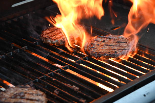 istock Three beef burgers being cooked on a gas fired barbecue with one burger surrounded with flames for a flamed grill burger 1397789156