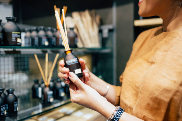 An anonymous smiling Asian female buying air freshener sticks at a store.