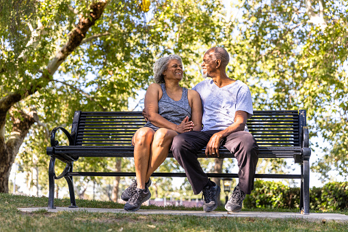 A senior black couple sitting and relaxing together at the park.