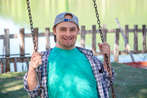Young boy with down syndrome smiling and looking at camera on a swing