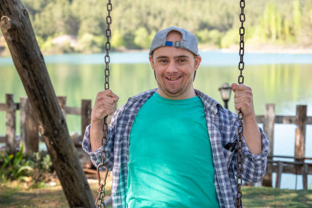 Young boy with down syndrome smiling and looking at camera on a swing