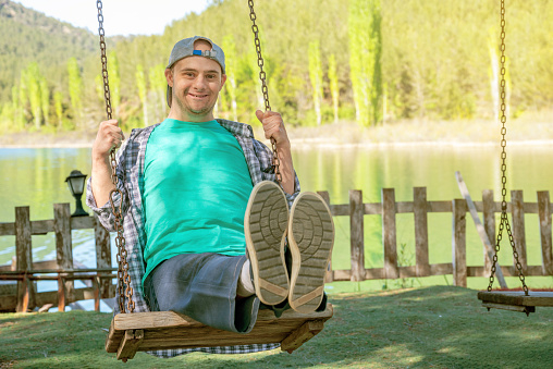 Young boy with down syndrome smiling and looking at camera on a swing