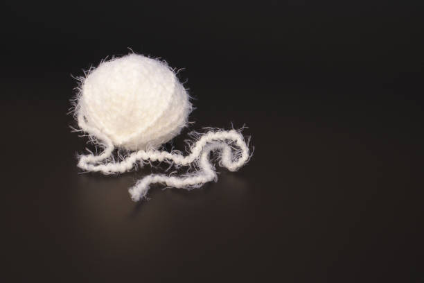 A ball of white thread for knitting on a black background.
