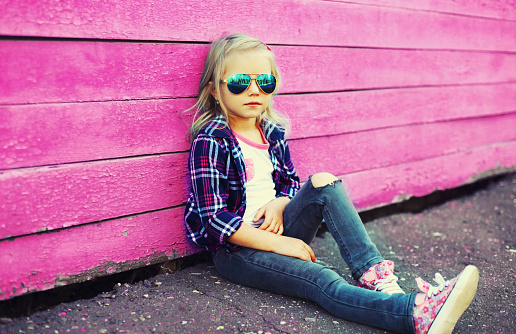 Portrait of stylish little girl child model posing on vivid pink background