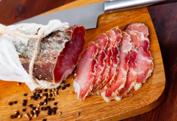 Sliced Polish cured sirloin pork polendvitsa on wooden cuting board. Traditional meat delicacies