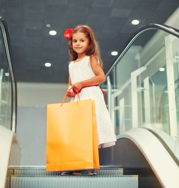 ショッピングモールで買い物袋を持った小さな女の子の子供の肖像画 - escalator child shopping mall little girls ストックフォトと画像