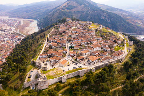 Aerial view of historical area of Berat on hilltop with medieval castle Scenic aerial view of historical area of Albanian city of Berat on hilltop surrounded by fortified walls of ruined medieval castle on spring day berat stock pictures, royalty-free photos & images