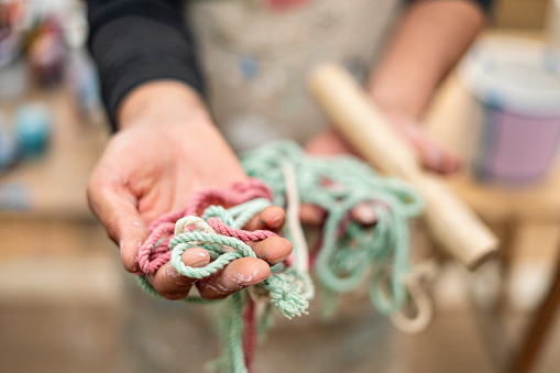 Close up shot of a man's hands in his workshop holding some macrame threads.