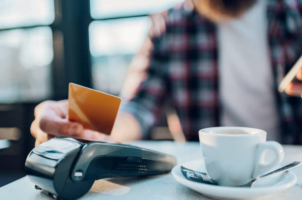 istock Man making transaction while using credit card and a payment terminal in a cafe 1397798941