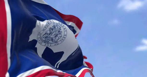 The US state flag of Wyoming waving in the wind. Wyoming is a state in the Mountain West subregion of the Western United States. Democracy and independence.