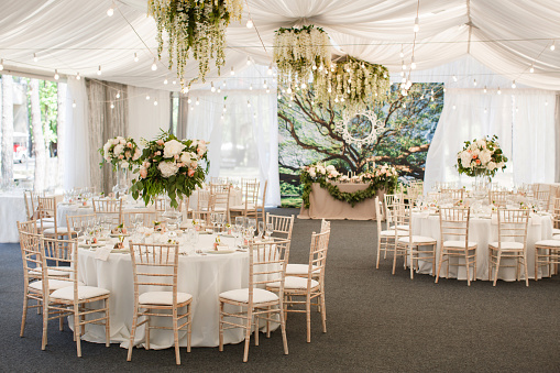 Wedding reception room with festively decorated tables with centerpiece flower arrangements