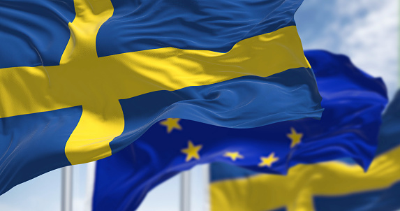 Detalle de la bandera nacional de Suecia ondeando al viento con la bandera borrosa de la Unión Europea en el fondo photo