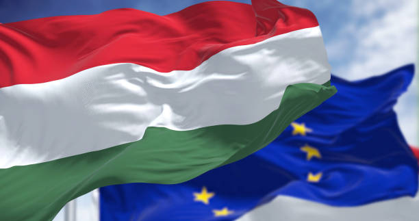 detalle de la bandera nacional de hungría ondeando al viento con la bandera borrosa de la unión europea en el fondo - hungarian flag fotografías e imágenes de stock