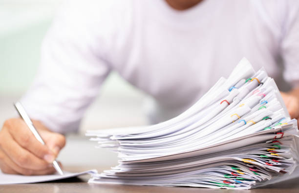istock Man in a white shirt sign contract agreement documents in Stack of Group report papers clipped in color clips in fair light, business, legal law and education concept 1397804382